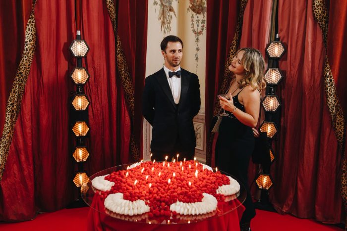 Black-tie guest beside the raspberry-and-cream signature cake at the Palácio do Grilo birthday