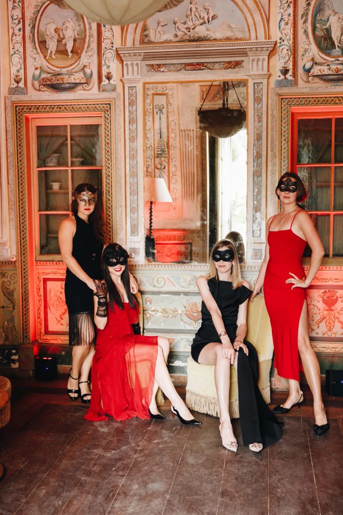 Guests in masquerade masks and black-tie dress in a frescoed salon at Palácio do Grilo